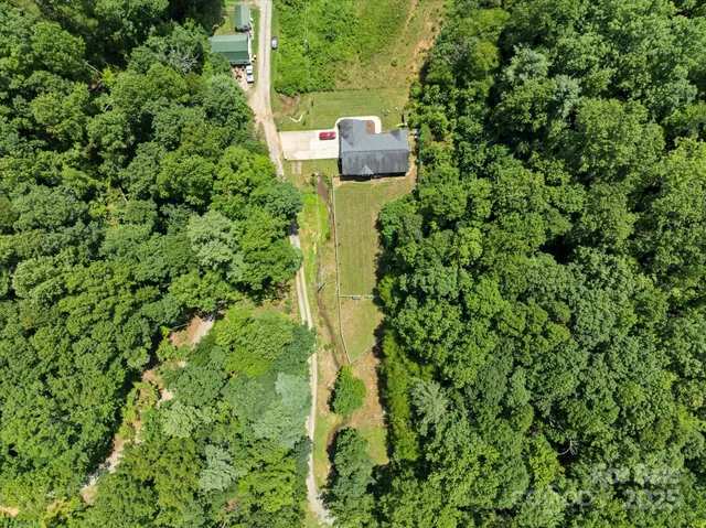 an aerial view of residential house with outdoor space and trees all around