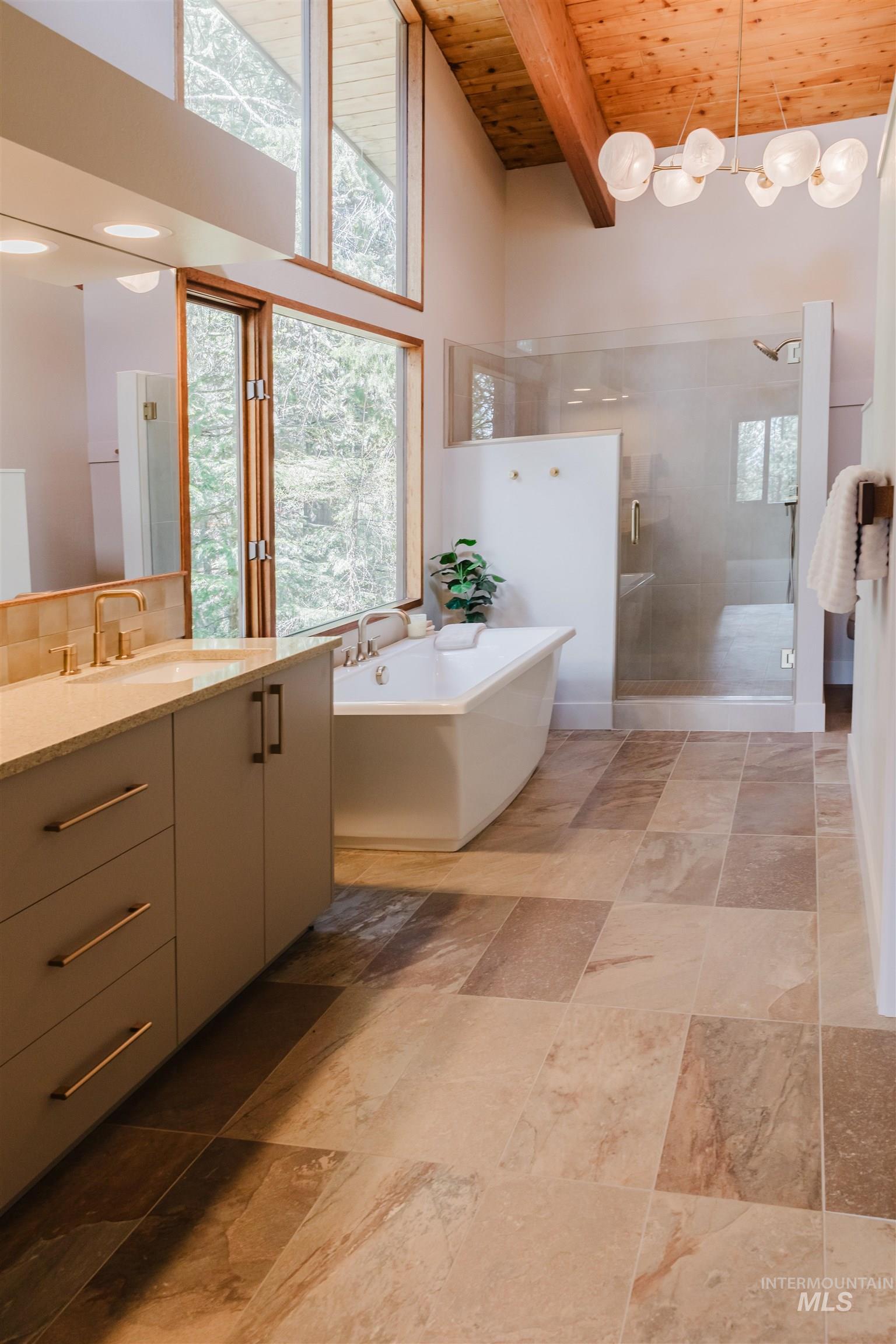 136 Silver Fox Trail McCall, ID 83638 - Photo 25 of 29 Vaulted wood-plank ceiling with exposed beams, full-height windows, freestanding soaking tub, glass-enclosed shower, and a double vanity with stone countertops