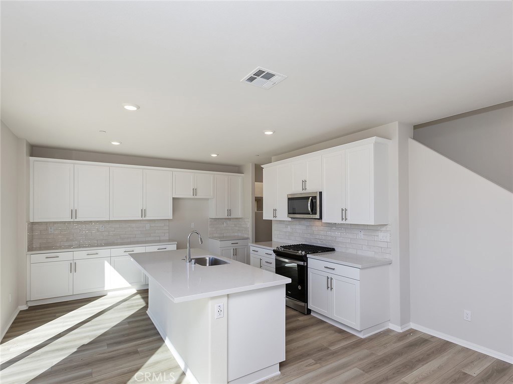 19557 Hanging Rock Road Lake Elsinore, CA 92532 - Photo 18 of 54 a kitchen with a sink a stove top oven and white kitchen