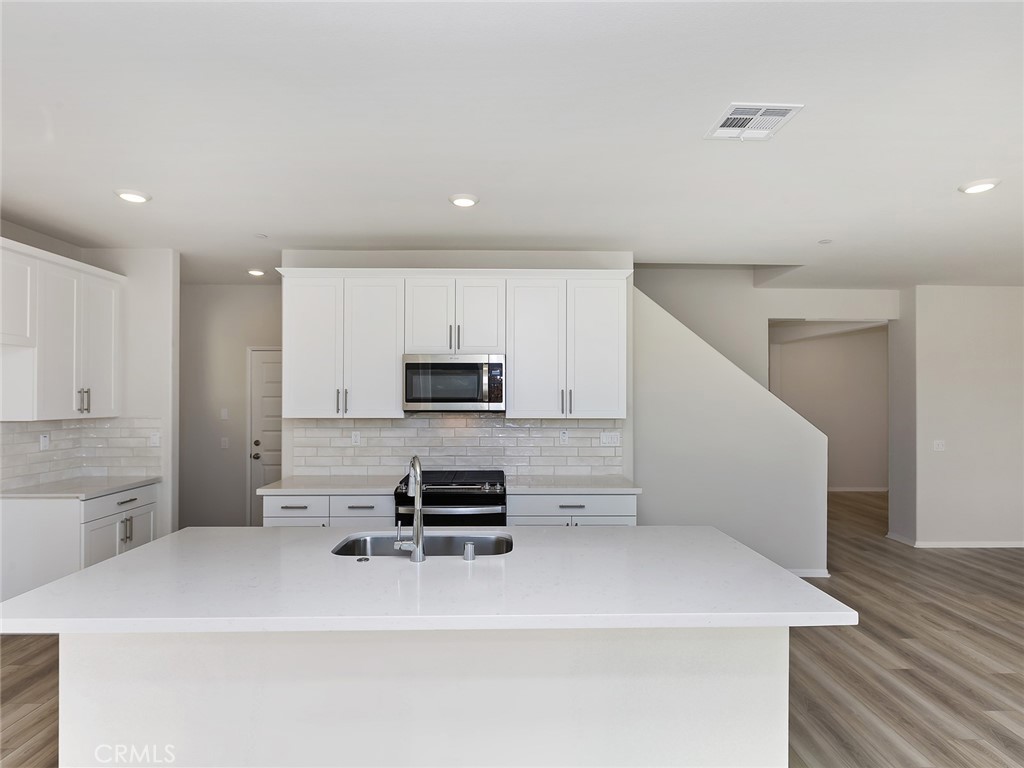 19557 Hanging Rock Road Lake Elsinore, CA 92532 - Photo 19 of 54 a kitchen with stainless steel appliances a sink a stove a microwave a refrigerator a stove and white cabinets