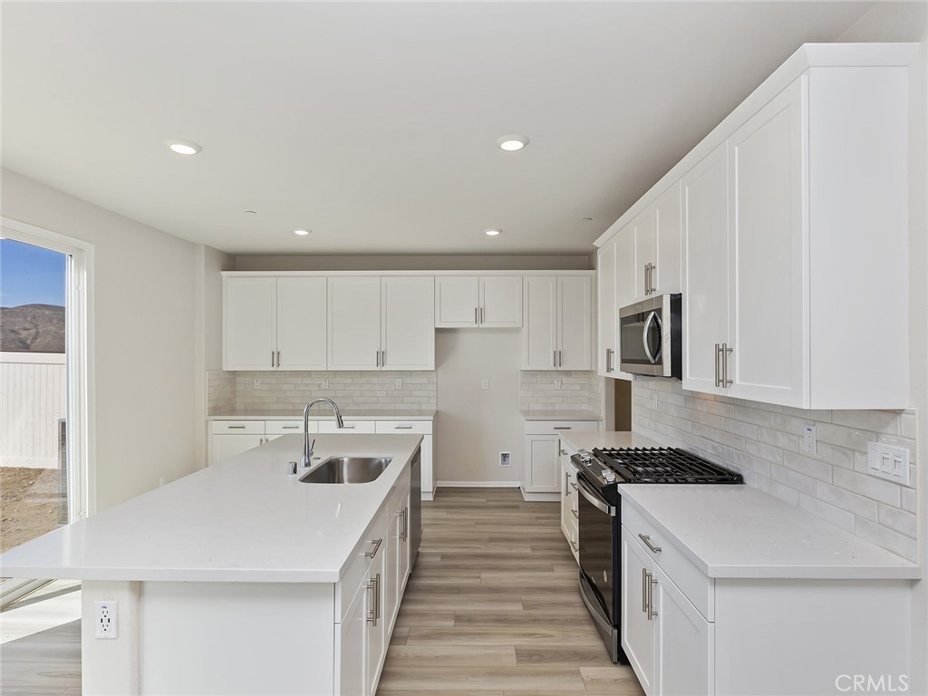 19557 Hanging Rock Road Lake Elsinore, CA 92532 - Photo 20 of 54 a kitchen with a sink stove and white cabinets