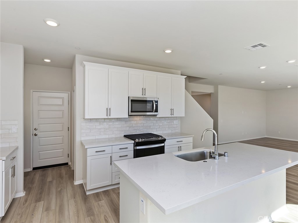 19557 Hanging Rock Road Lake Elsinore, CA 92532 - Photo 21 of 54 a kitchen with a sink a stove and cabinets