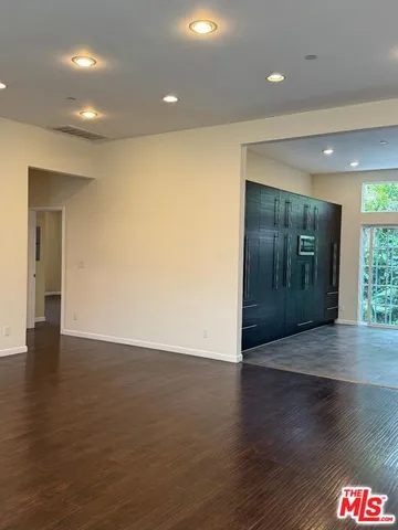an empty room with wooden floor and windows with curtains