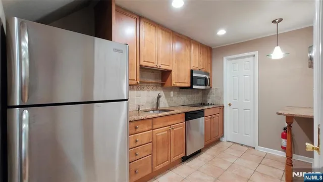 a kitchen with stainless steel appliances granite countertop a refrigerator a stove top oven and a sink