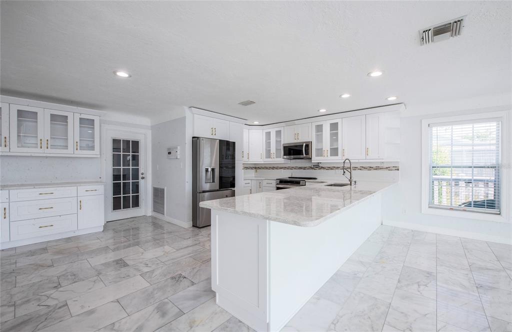 551 Crystal Drive Madeira Beach, FL 33708 - Photo 22 of 46 a large white kitchen with stainless steel appliances kitchen island a stove a sink a refrigerator and a cabinets