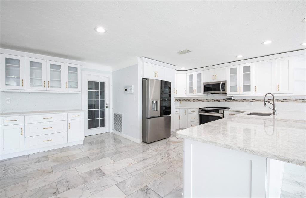 551 Crystal Drive Madeira Beach, FL 33708 - Photo 28 of 46 a kitchen with stainless steel appliances a refrigerator stove microwave and sink