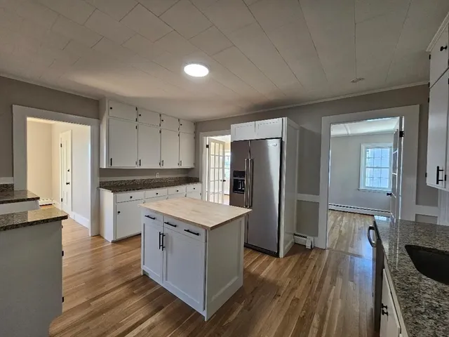 a kitchen with a refrigerator a sink and wooden floor