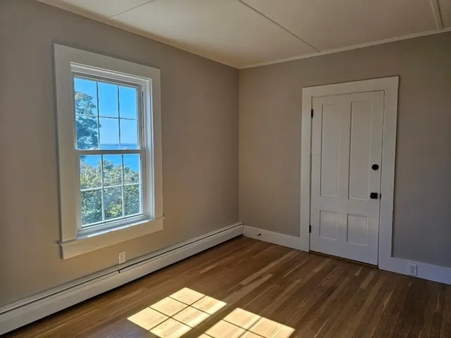 an empty room with wooden floor closet and windows