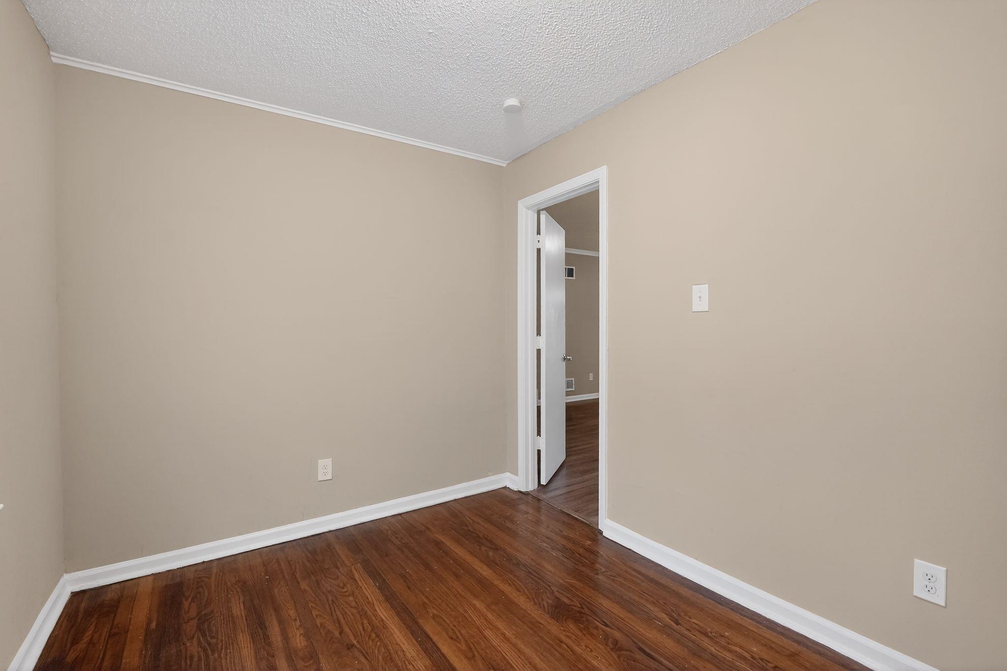 4689 Raleigh Lagrange Road Memphis, TN 38128 - Photo 12 of 30 Empty room featuring dark wood-style floors and a textured ceiling