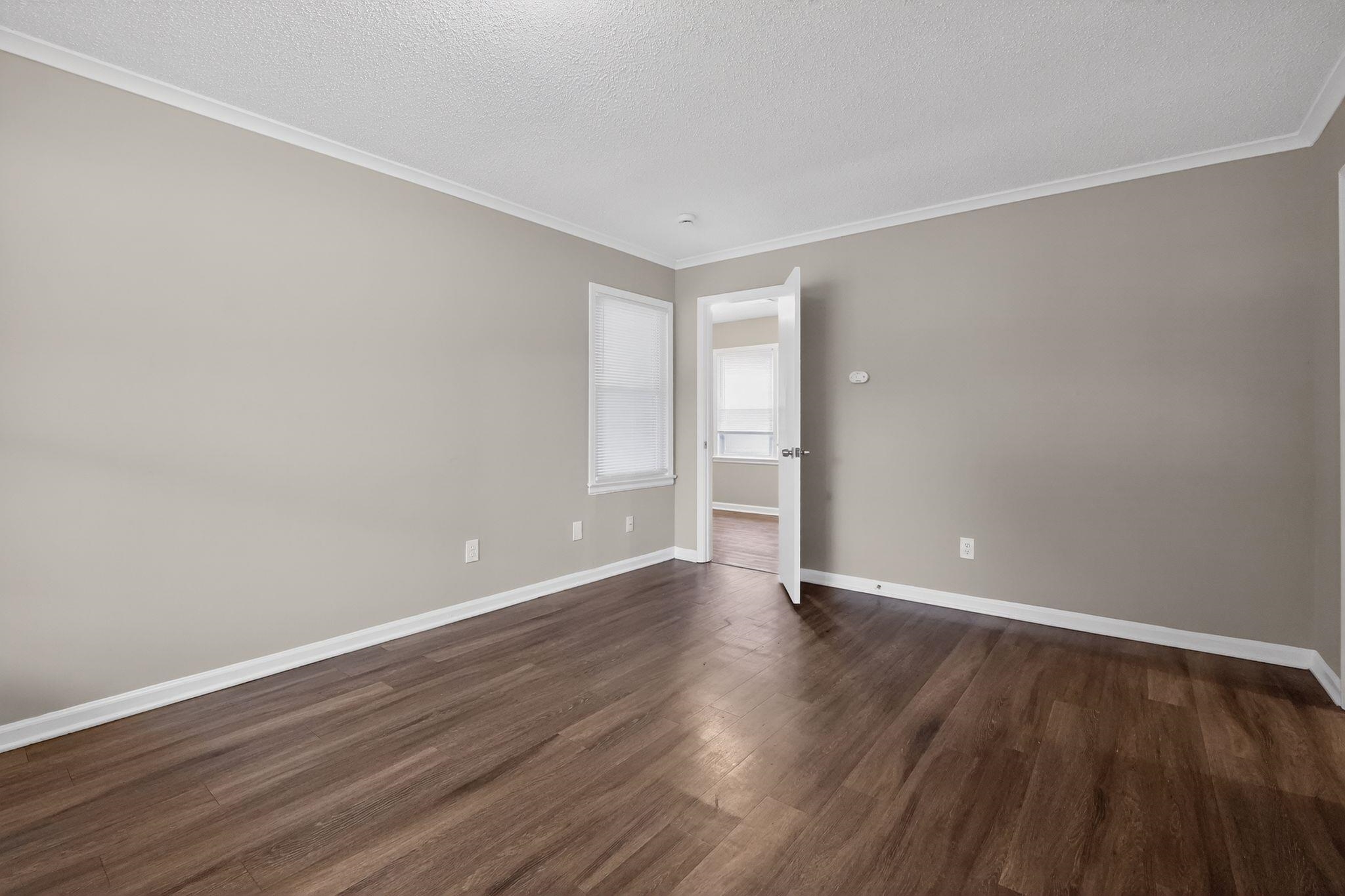 4689 Raleigh Lagrange Road Memphis, TN 38128 - Photo 10 of 30 Empty room featuring dark wood-style floors, crown molding, and a textured ceiling