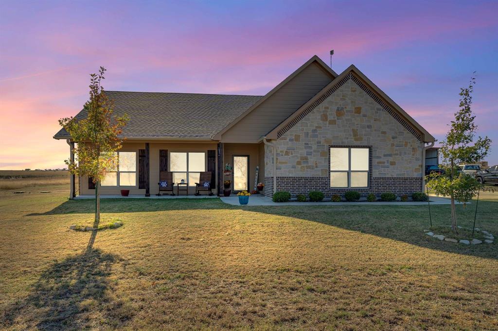 View of front of property featuring a porch, a front yard, and stone siding