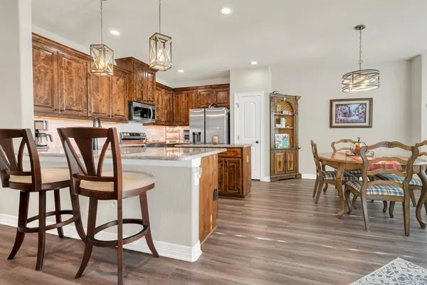 a kitchen with stainless steel appliances granite countertop a table chairs stove and refrigerator
