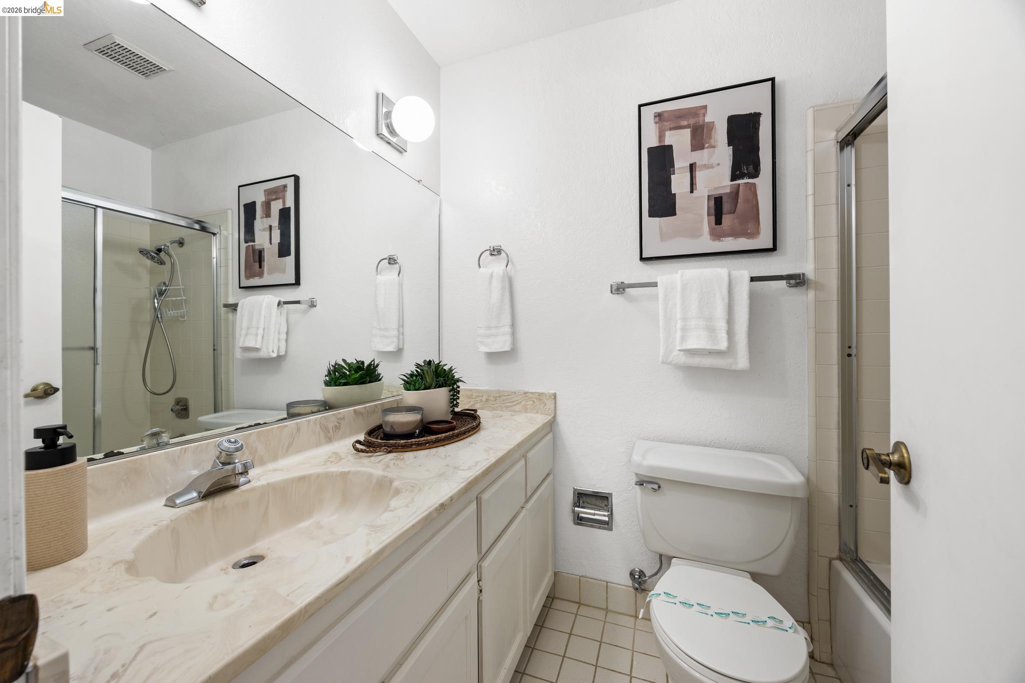 201 Vista Heights Road El Cerrito, CA 94530 - Photo 17 of 32 Bathroom featuring a single vanity with an integrated sink, a rectangular mirror, a shower-tub combination with a sliding glass door, and square tiled flooring