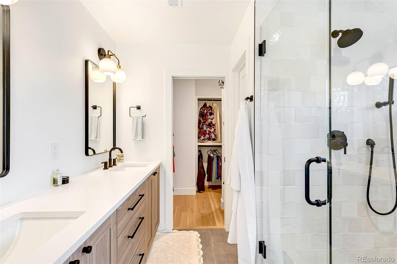 2455 Chase Street Edgewater, CO 80214 - Photo 22 of 46 a bathroom with a double vanity sink a mirror a shower and a bathtub