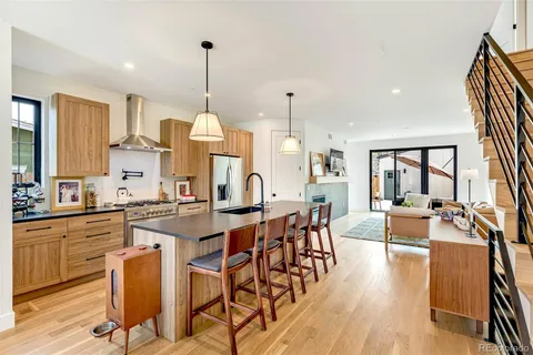 a kitchen with stainless steel appliances kitchen island granite countertop a stove a sink dishwasher and white cabinets with wooden floor