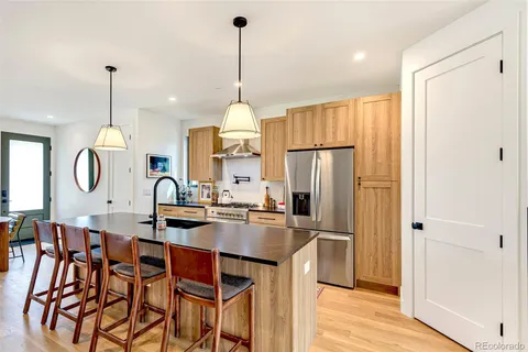 a kitchen with kitchen island granite countertop a table a stove a refrigerator and cabinets