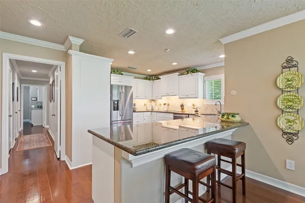 a kitchen with stainless steel appliances granite countertop a dining table chairs and refrigerator
