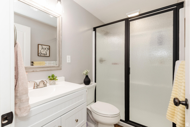 972 West 2840th Street South Logan, UT 84321 - Photo 29 of 46 Contemporary bathroom featuring a white vanity with a single basin, a framed mirror, and a shower enclosure with a dark frame and textured glass