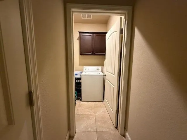 a view of a hallway with a white cabinet and a mirror