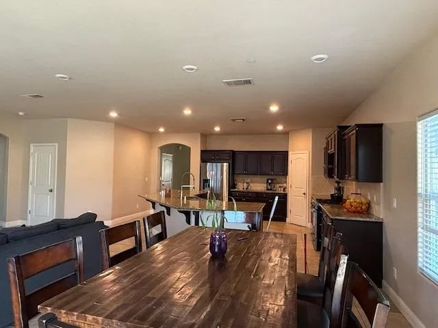 a living room with stainless steel appliances furniture a rug and a kitchen view
