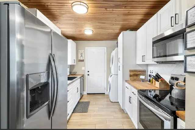 a kitchen with stainless steel appliances granite countertop a refrigerator a stove and a wooden cabinets