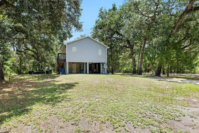 a view of a house with a yard and large trees