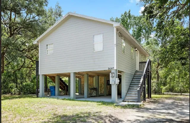 a view of a house with a backyard and floor to ceiling window and large tree