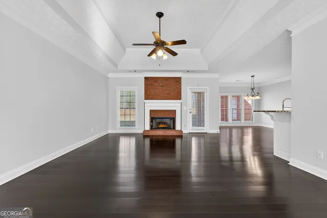 a view of an empty room with wooden floor fireplace and windows