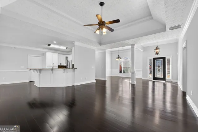 a view of an empty room with wooden floor and a ceiling fan