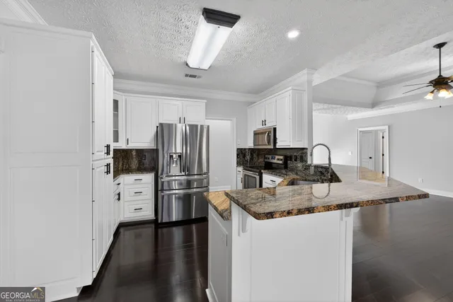 a kitchen with refrigerator a stove a sink cabinets and wooden floor