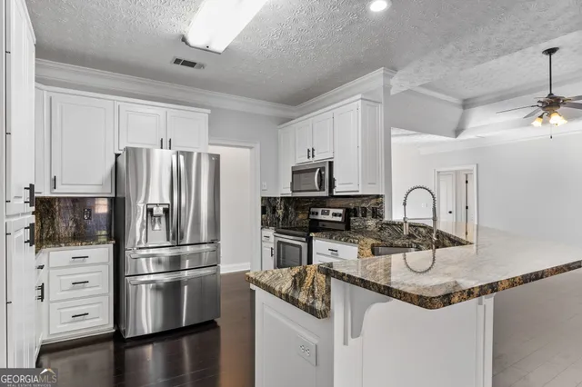 a kitchen with stainless steel appliances granite countertop a refrigerator sink and stove