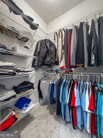 a view of walk in closet with clothes and shoes