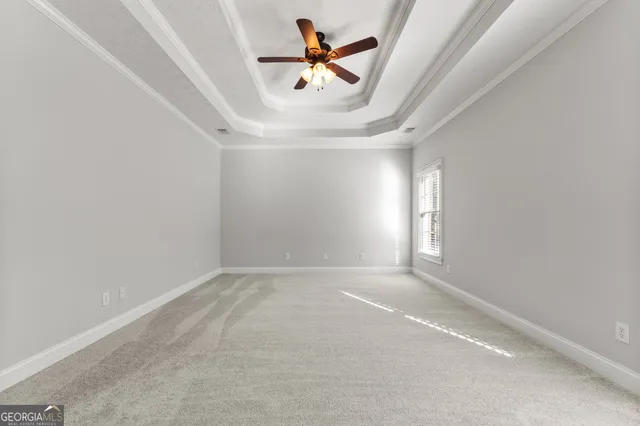 an empty room with chandelier fan and windows