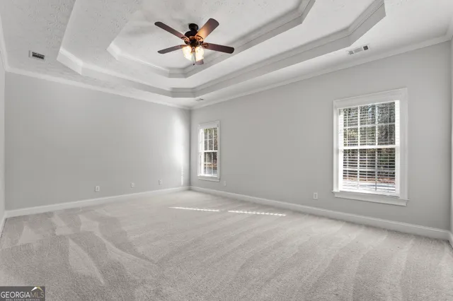 an empty room with windows and ceiling fan