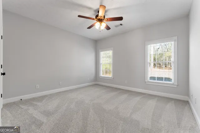 an empty room with windows and chandelier fan