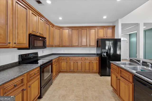 a kitchen with stainless steel appliances granite countertop a refrigerator stove top oven and sink