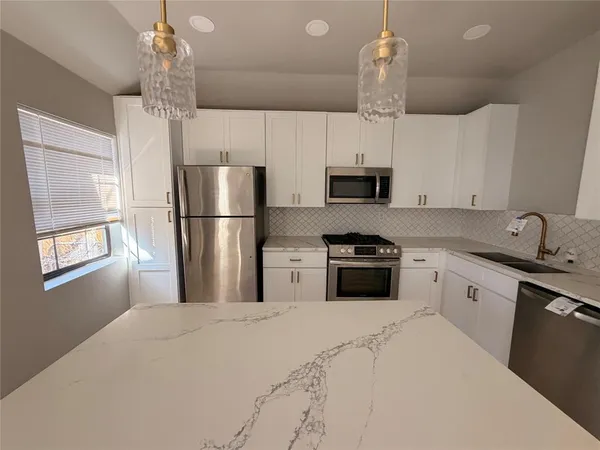 a kitchen with kitchen island a sink stainless steel appliances and window