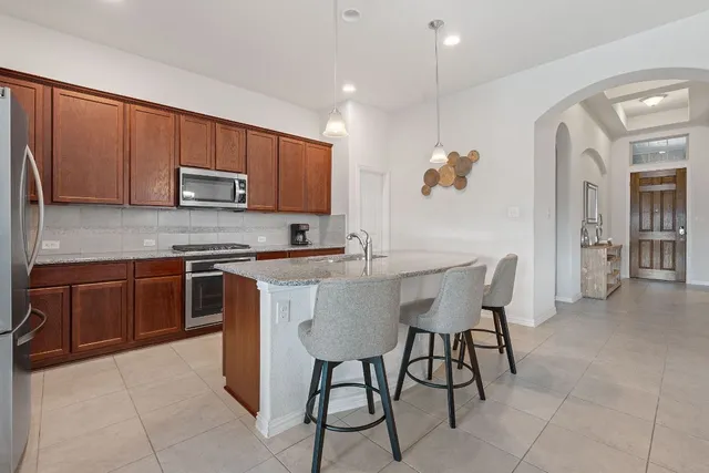 a kitchen with stainless steel appliances granite countertop a stove top oven a sink a refrigerator and a microwave