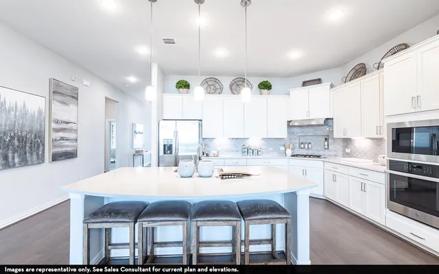 a kitchen with a dining table chairs sink and white cabinets