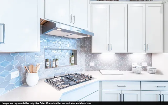 a kitchen with granite countertop a stove a sink and white cabinets with wooden floor