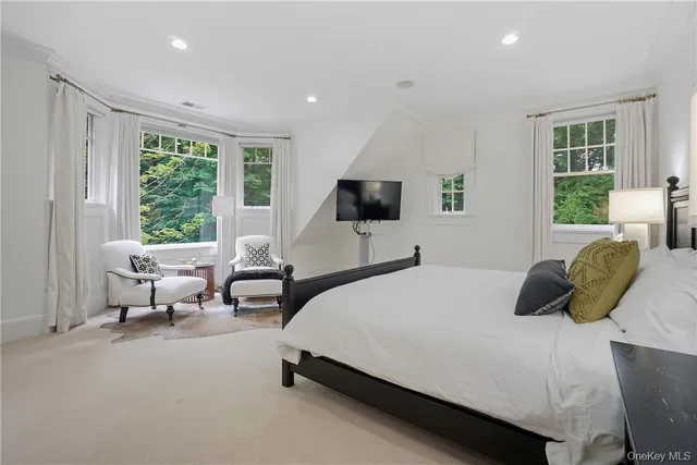 a bedroom with a bed and large windows