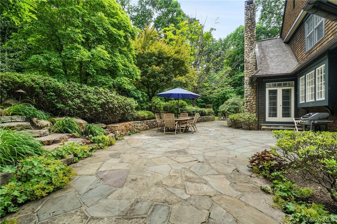 8 Brady Road Bedford Corners, NY 10549 - Photo 27 of 30 a view of a patio with table and chairs under an umbrella with large trees