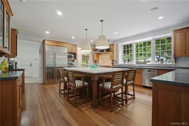 a kitchen with stainless steel appliances granite countertop a stove a sink a refrigerator and a wooden cabinets