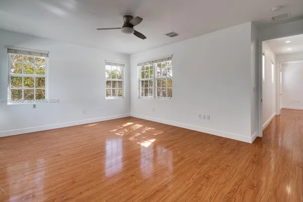 a view of empty room with wooden floor and fan