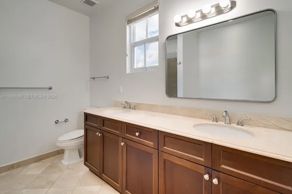 a bathroom with a double vanity sink toilet and a mirror