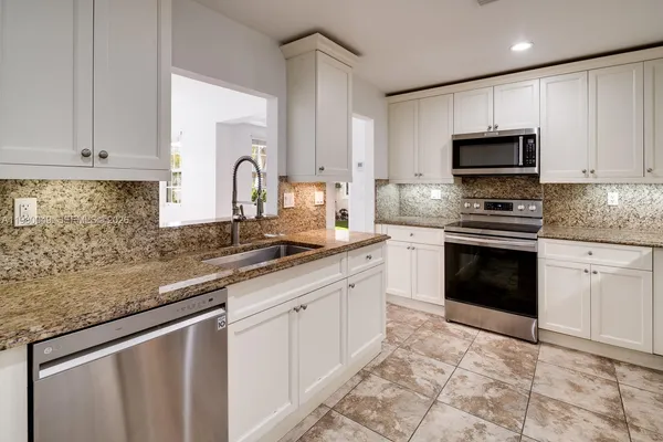 a kitchen with granite countertop a sink stove and cabinets
