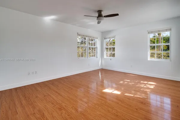 an empty room with wooden floor and windows
