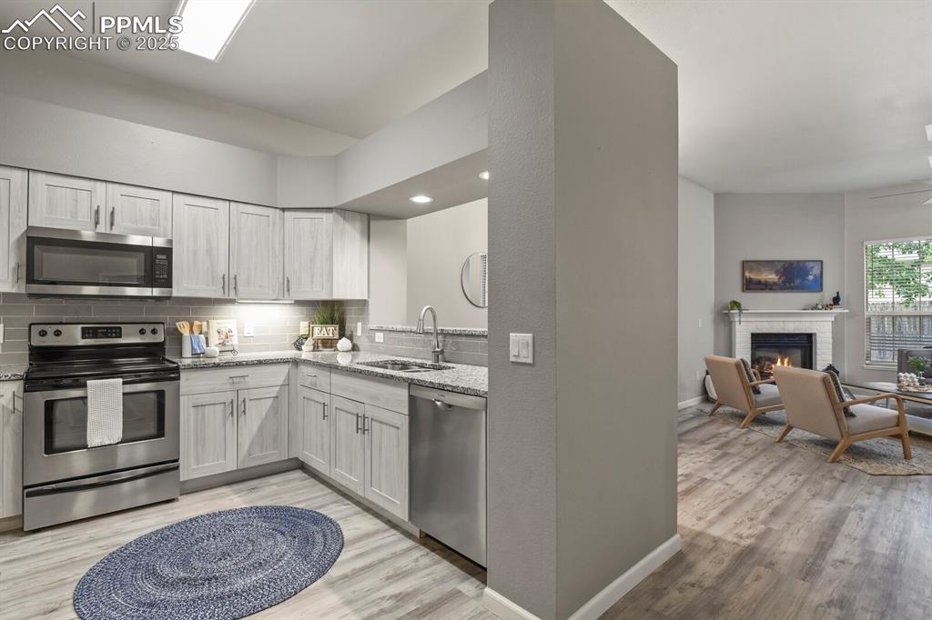 6868 Los Reyes Circle Colorado Springs, CO 80918 - Photo 13 of 47 a kitchen with stainless steel appliances granite countertop a stove top oven a sink dishwasher and a refrigerator with wooden floor