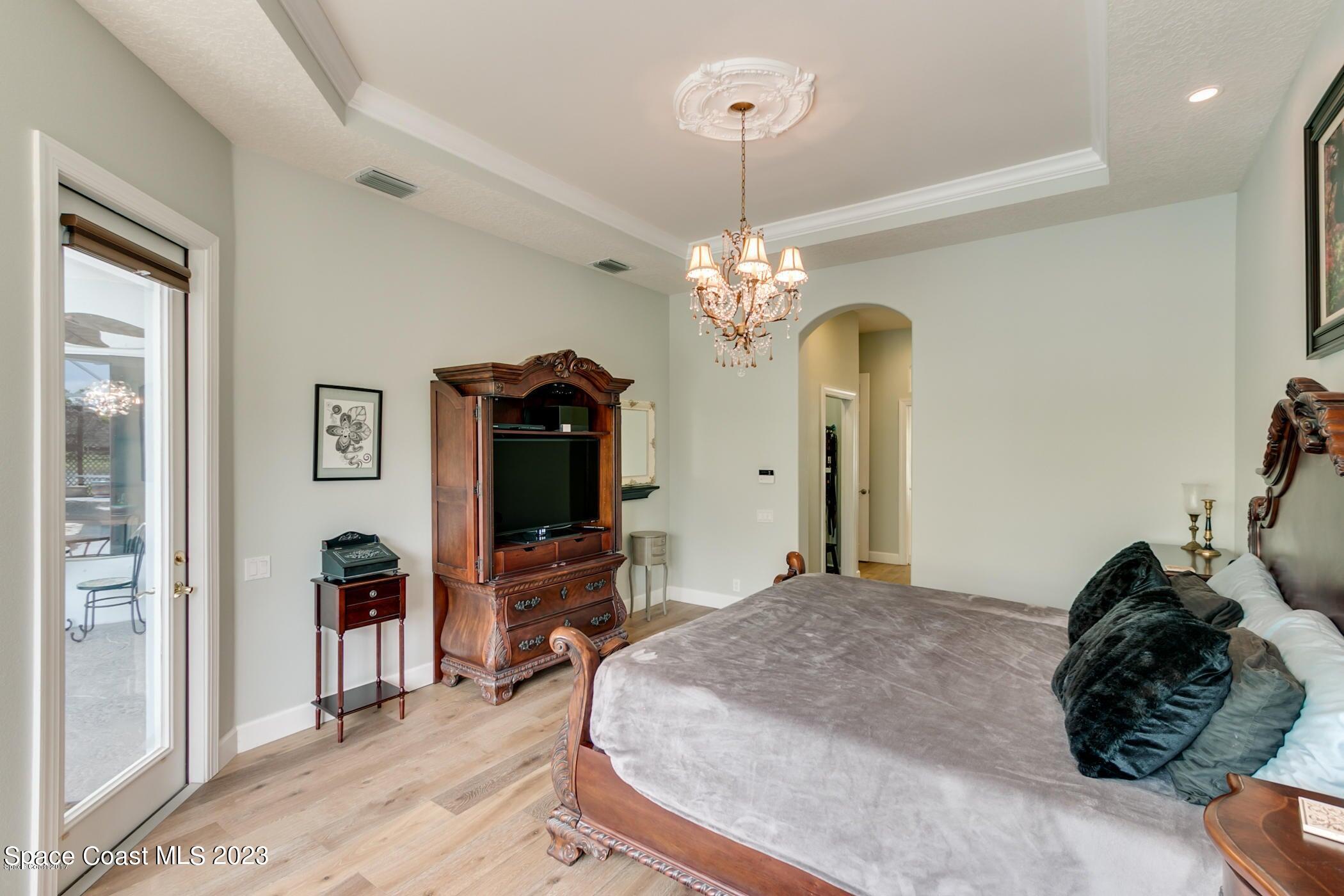 1840 Winding Ridge Circle Southeast Palm Bay, FL 32909 - Photo 26 of 41 a bedroom with a bed and a chandelier