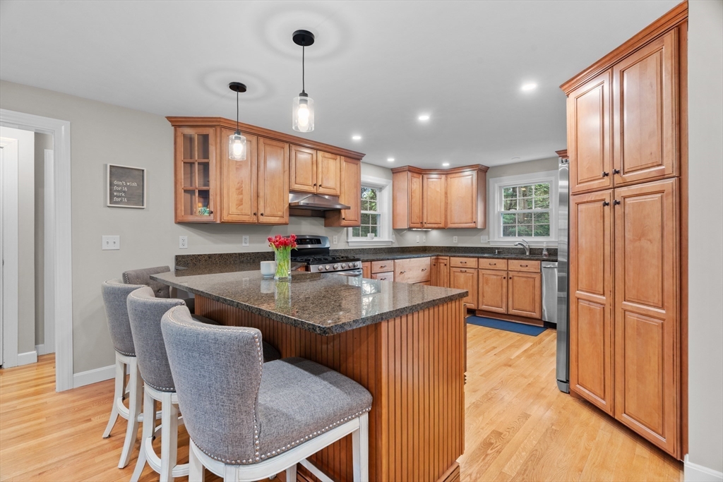 26 Cushing Road Westwood, MA 02090 - Photo 9 of 42 a kitchen with stainless steel appliances granite countertop a stove a sink a microwave a dining table and chairs